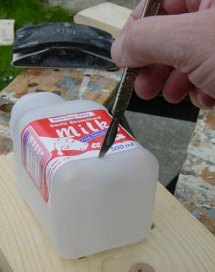 Photo, cutting the bottom out of a plastic milk container