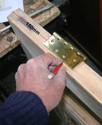 Marking the position of the top hinge on the door edge.