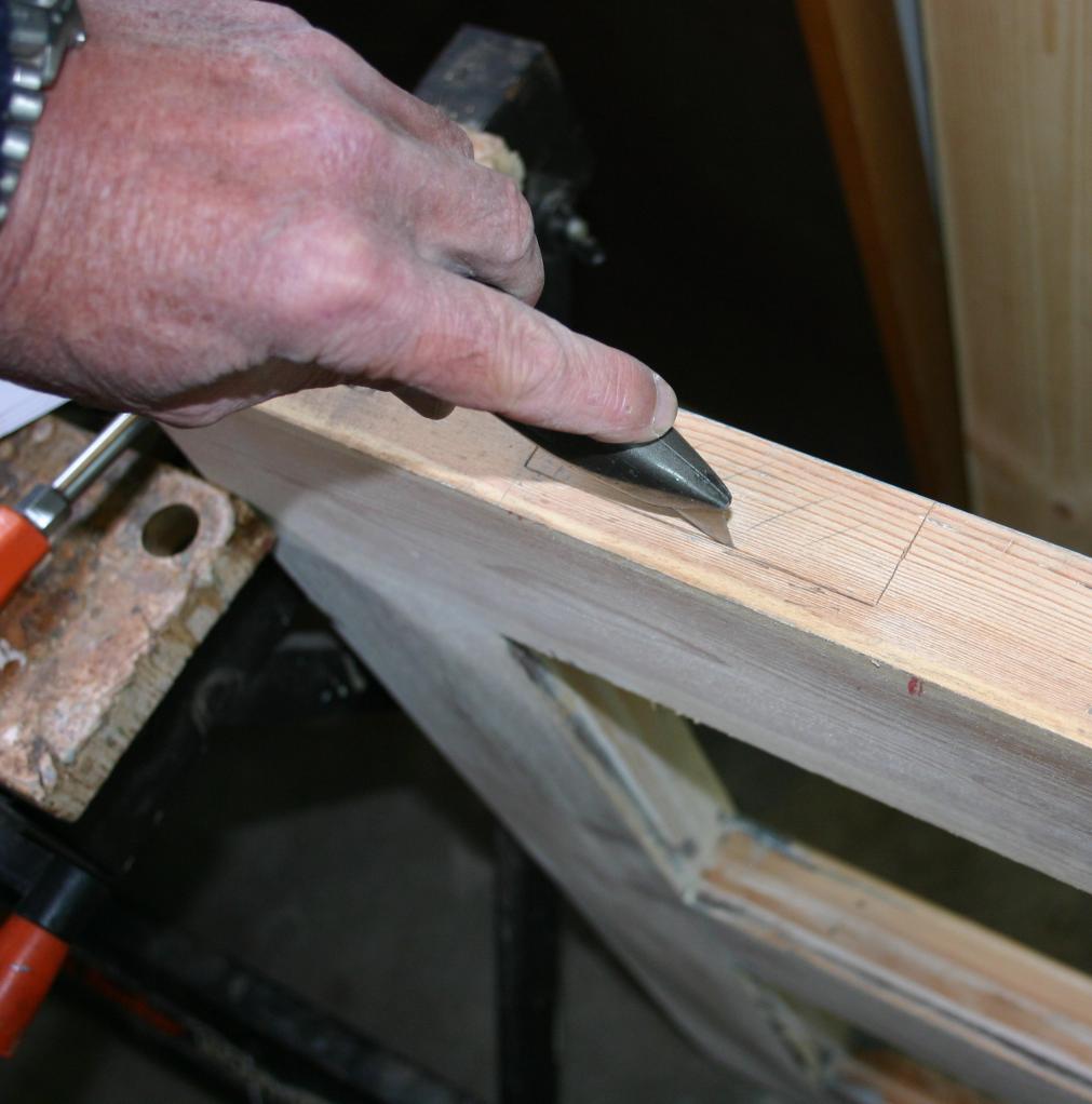 Using a craft knife to incise along the pencil boundary of the top hinge outline on the door edge.