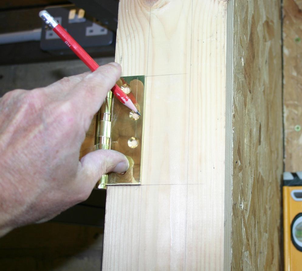 Outlining the position of the hinge on the door frame.
