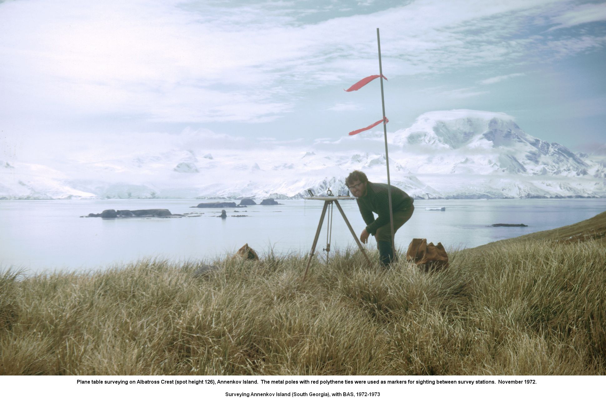 Plane table surveying on Albatross Crest (spot height 126), Annenkov Island.  The metal poles with red polythene ties were used as markers for sighting between survey stations.  November 1972.