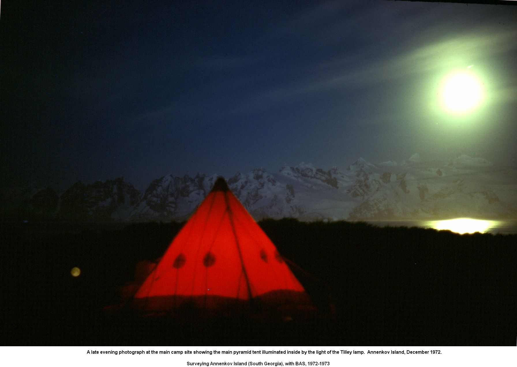 A late evening photograph at the main camp site showing the main pyramid tent illuminated inside by the light of the Tilley lamp.  Annenkov Island, December 1972.