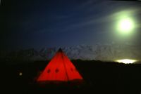 A late evening photograph at the main camp site showing the main pyramid tent illuminated inside by the light of the Tilley lamp. Annenkov Island, December 1972.