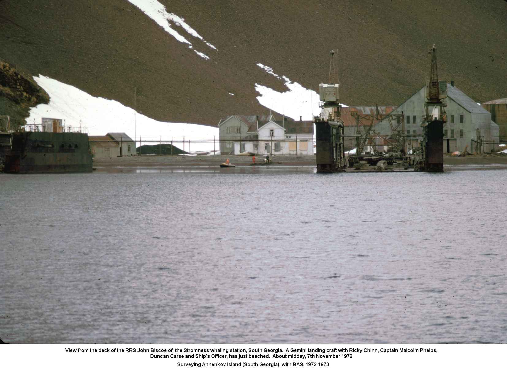 View from the deck of the RRS John Biscoe of  the Stromness whaling station, South Georgia.  A Gemini landing craft with Ricky Chinn, Captain Malcolm Phelps,
Duncan Carse and Ship's Officer, has just beached.  About midday, 7th November 1972.